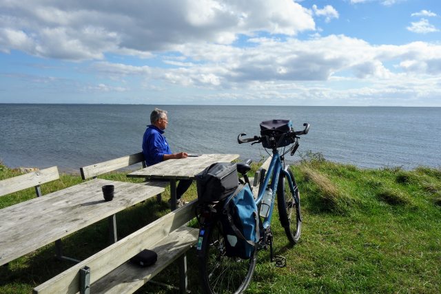 Een fietser geniet op het Deense eiland Hjarnø van het uitzicht over zee. 