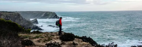 Wandelaar kijkt uit over de Atlantische Oceaan vanaf een klif aan de Portugese kust.