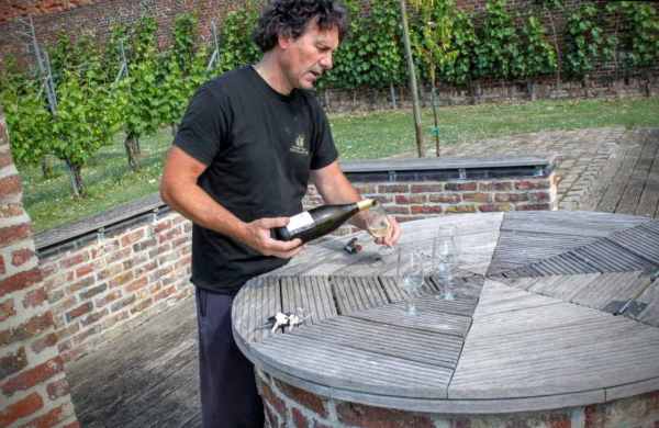 Peter Colemonts schenkt wijn in van wijngaard Clos d'Opleeuw