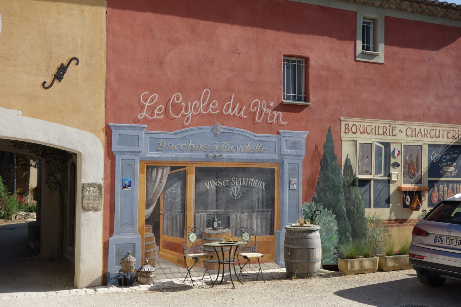 Een denkbeeldig café met de titel Le Cycle du Vin, te zien vanaf een fietspad in Luberon.