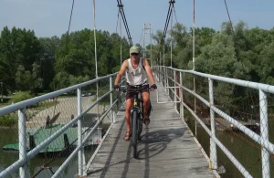 Fietser balanceert op een voetgangersbrug over de Drava