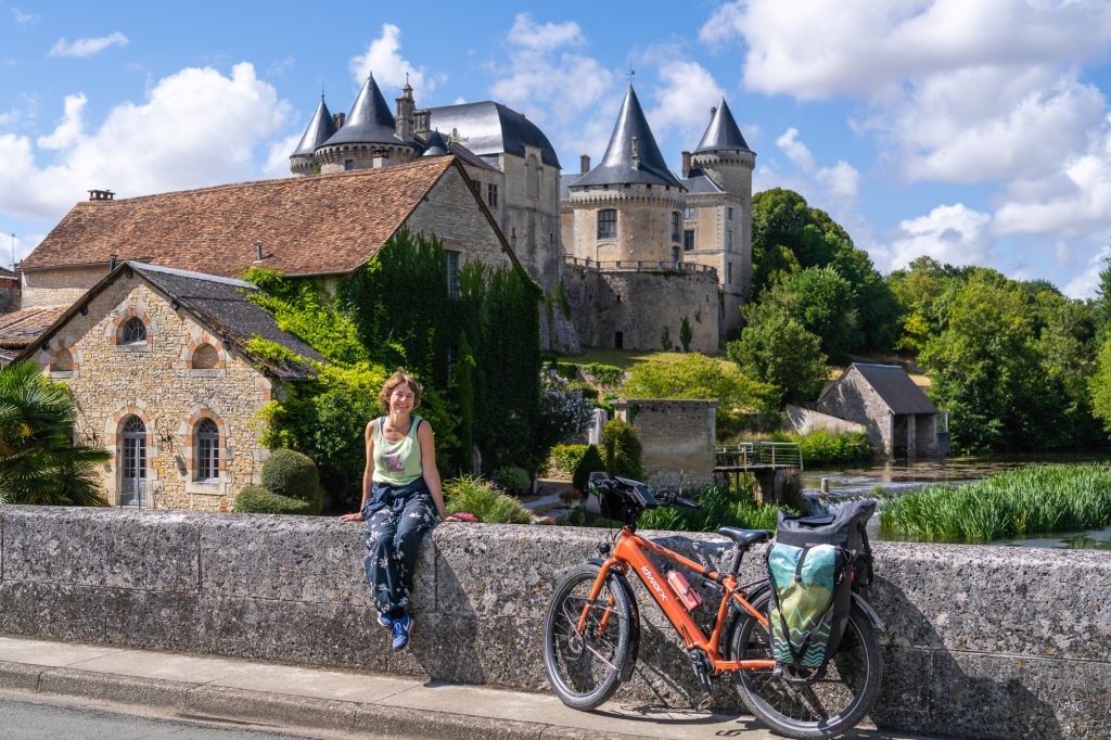 Fietser op een stenen muurtje van een brug in Frankrijk
