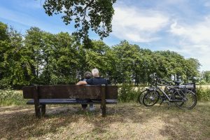 Twee fietsers rusten uit op een bankje langs de Grebbelinie