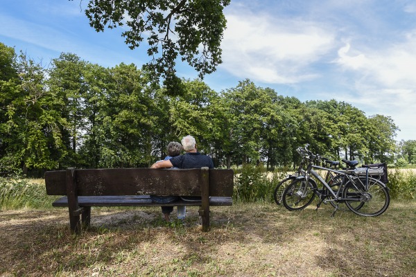 Twee fietsers rusten uit op een bankje langs de Grebbelinie