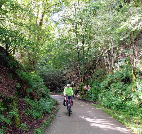 Een fietser met geel windjack op het traject van een voormalige spoorlijn in Luxemburg