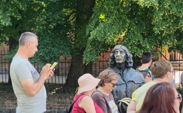 Het bronzen beeld van Copernicus in Olsztyn, omringd door toeristen