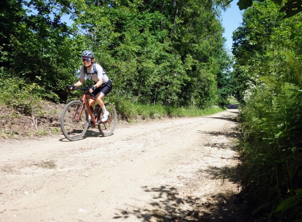 Vrouw op een gravelbike fietst over een landweg in Polen